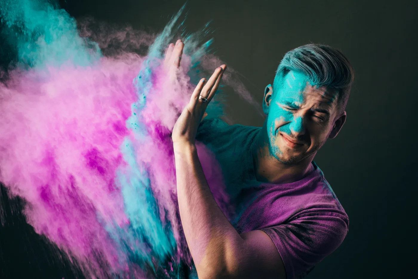 Portrait of Jeff Hodges with bursts of pink and teal powder against a dark studio background